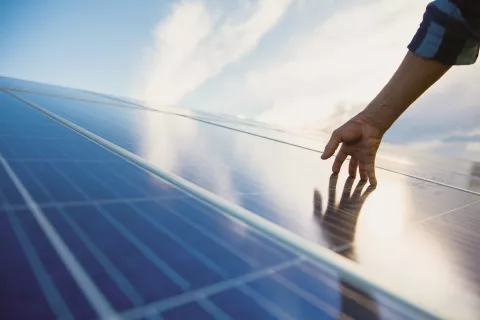 Person berührt Photovoltaikanlage